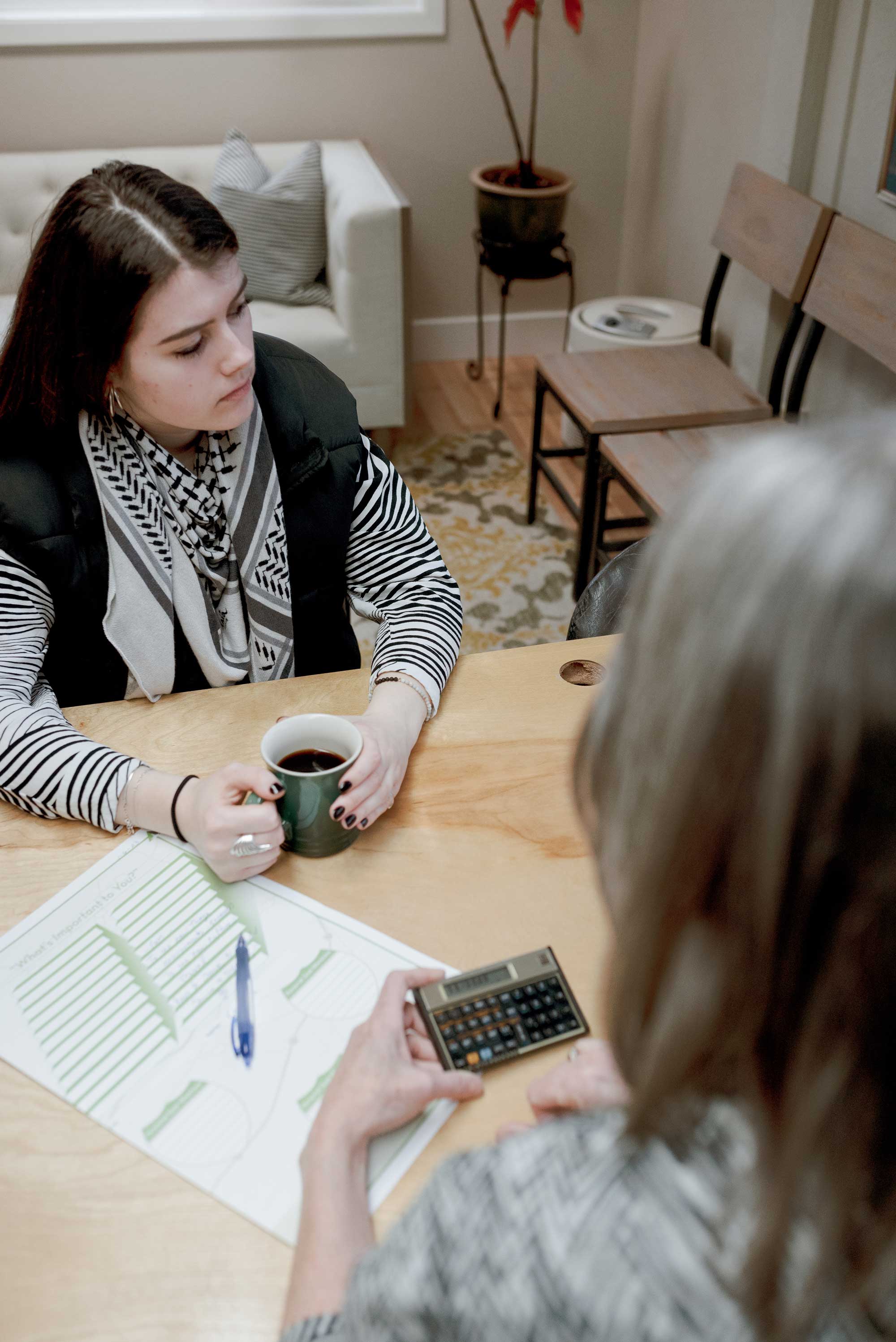 veronica holding coffe mug while cyndy is using calculator